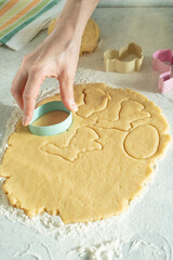 Female model cut dough with cookie cutter on kitchen table