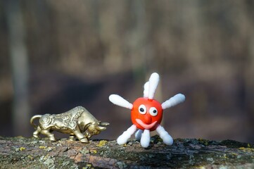 A metal bull and a plasticine virus figurine.