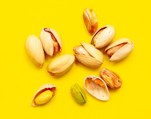 Close-up of fresh pistachio nuts on a yellow background.