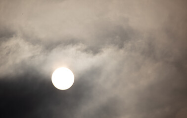 The sun shines behind the clouds during