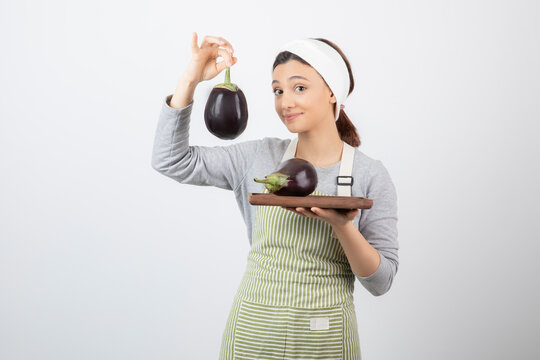 Picture of a nice young woman model in apron holding an eggplant