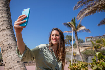 Fototapeta na wymiar A beautiful tourist takes a selfie during her summer vacation in a tropical place
