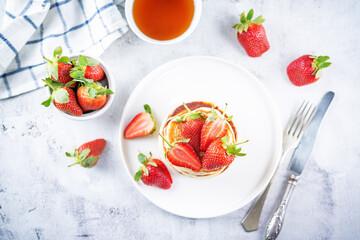 Pancakes decorated with strawberries in a plate