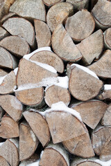 Close up of chopped firewood pile for winter covered with snow