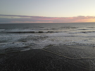 sunset in the atlantic ocean coast of argentina. waves with foam and beautiful sky colors