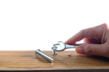 Jjoiner hand with a wrench screwing a furniture screw into a wooden plank at white background, The...