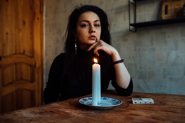 the girl is guessing on a lighted candle and cards, predicting the future and fate