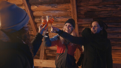 Cheers. Young women, best friends having a party at mountain wooden house. High quality photo