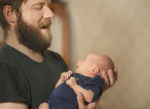 Dad Talks To His Newborn Son. The Child Attentively Listens To The Father, Mutual Understanding. A Lullaby Song.