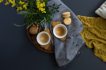 Overhead view of a couple of coffee cups over wooden cloud shaped trays with a yellow blanket at the right part.