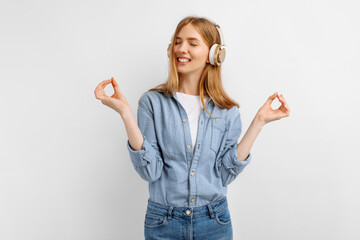 Obraz premium Cheerful young woman listening to music on headphones over white background