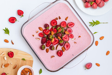 Homemade cheesecake with strawberries and berries in a glass dish on a white table