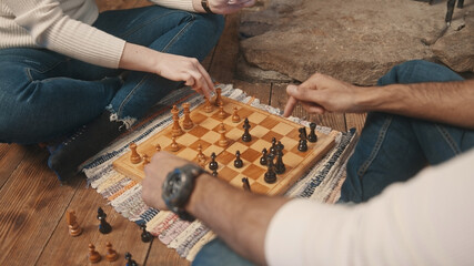Young couple playing chess on the floor of the oczy home, close up. High quality photo