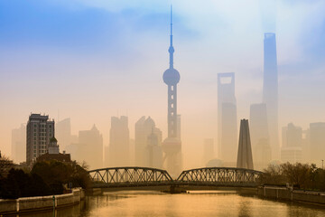Shanghai Financial Center and modern skyscraper city in misty gold lighting sunrise behind pollution haze, view from the bund in Shanghai, China. vintage picture style