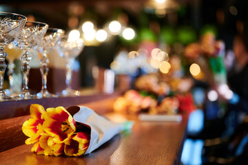 Bouquet of yellow tulips on the bar among the glasses of the restaurant