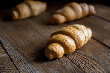 Fragrant croissant on a wooden background. Sweets for tea or coffee