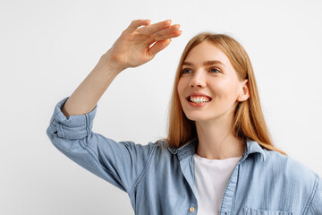 Young woman stands and looks into the distance, on a white studio background