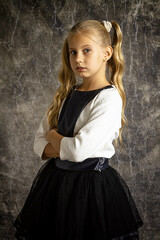 Portrait of a blonde girl in black and white clothes on a gray background, studio shooting.