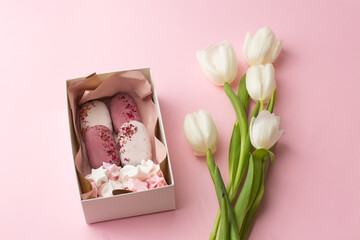 Delicious handmade ice-cream in a gift box isolated on pink background with white tulips. Sweet present, beautiful flowers, pink colors, flat lay. International women's day, birthday.