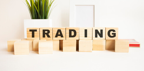 Wooden cubes with letters on a white table. The word is TRADING. White background.