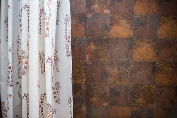 Shower curtain with cat cartoon pattern over blurred brown tile texture backgrund, interior design, bathroom design