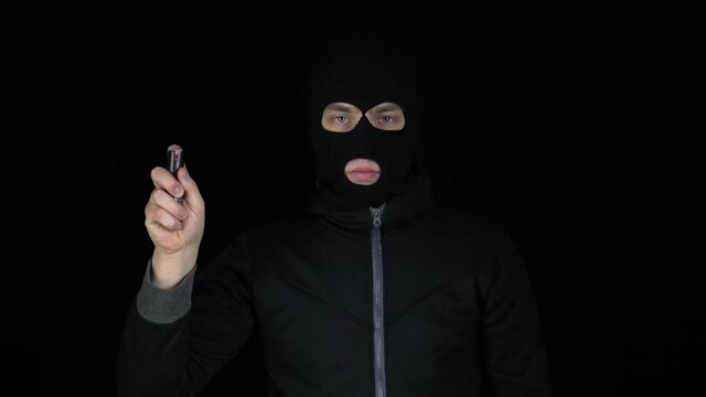 A man in a balaclava mask stands with a pepper spr