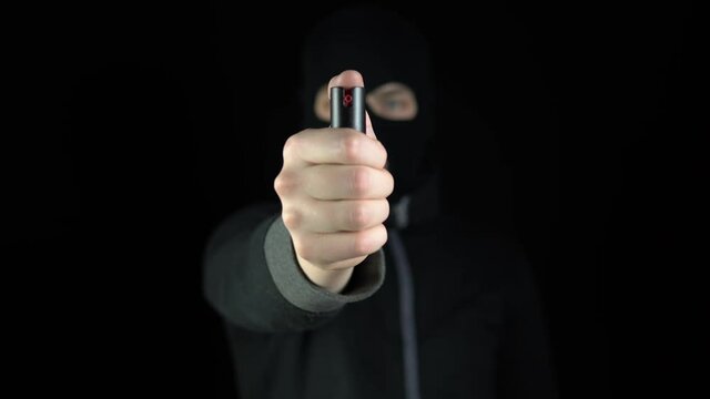 A man in a balaclava mask stands with a pepper spr