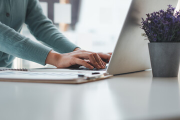 Business woman working and typing on laptop computer on the table.