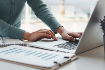 Business woman working and typing on laptop computer on the table.