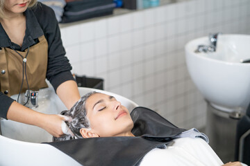 Beautiful Caucasian women feel relax and comfortable while getting hair wash with shampoo and...