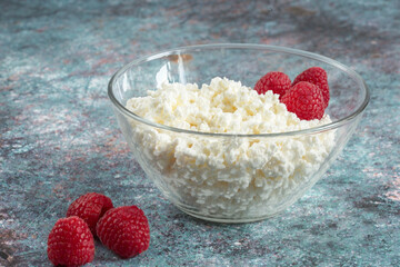 Cottage cheese in a glass bowl. On a  turquoise background. Dietary product. The concept of healthy eating.