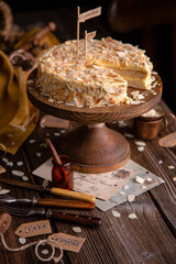 tasty homemade cake with two biscuit layers, white cream and almond flakes on wooden cake stand on rustic table