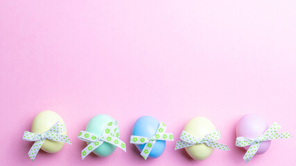 Easter holiday. Colourful egg with tape ribbon on pastel pink background in Happy Easter decoration. Spring holiday top view with copy space.