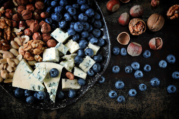 A plate with cheese, nuts and blueberries. Healthy snack. Cheese plate. Keto snack. Keto dessert.