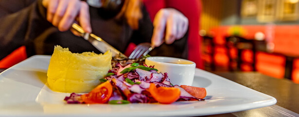 woman hands with fork and knife eating beef steak in cafe
