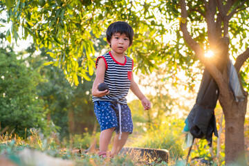 Boy playing in green nature park sunset light