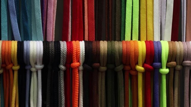 different colors of laces or rope on the shelves of a clothing factory