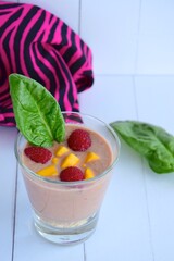 smoothie in glass with raspberry, mango, chia seeds and spinach