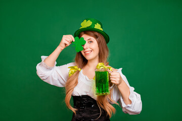 Portrait of a woman in a festive st patrick's day costume and hat holding a mug of green beer and a...