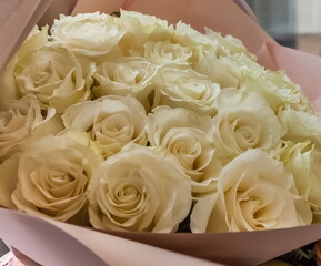 Bouquet of white flowers roses in pink paper closeup