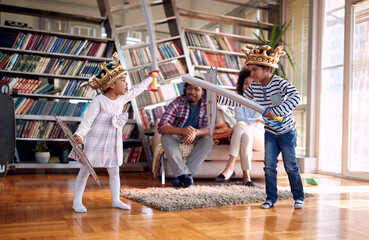 Kids playing with swords and enjoying with parents at home. Family, together, love, playtime