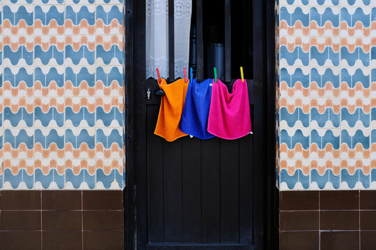 towels in a row on clothesline admist portuguese azulejos on wall