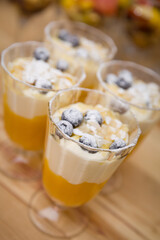 Glass goblets with delicious dessert at the party. Blueberries, smoothies and the most delicate yogurt.