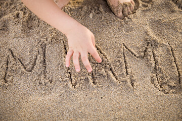 Cute kid wrote the word Miami in the sand. Vacation concept. Selective focus