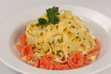 Fettuccine pasta with salmon on a white background