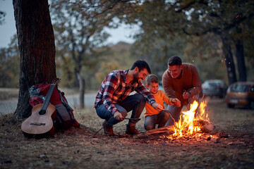 Child with dad and grandpa preparing campfire