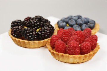 Three baskets of fresh raspberries, blueberries and blackberries.