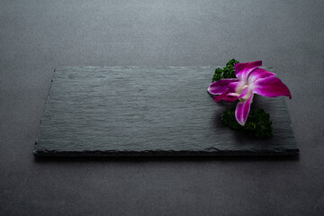 Black slate tray decorated with orchids and parsley