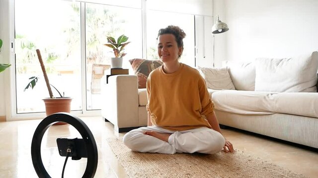 Cheerful woman performing breath works in Lotus pose at home