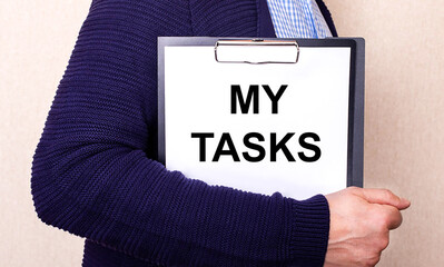 MY TASKS is written on a white sheet held by a man standing sideways